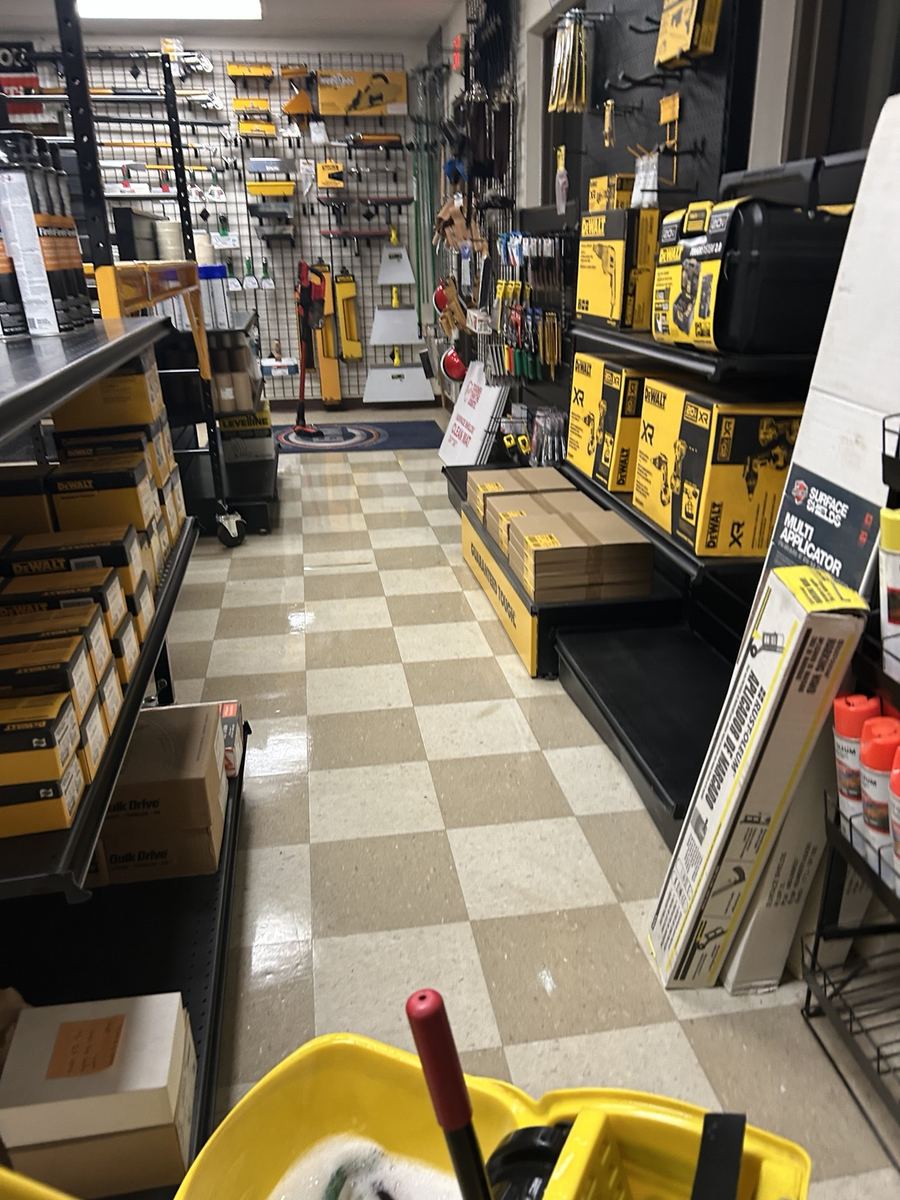 Retail aisle floor being cleaned with mop bucket nearby